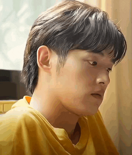 a close up of a man 's face with a yellow shirt on