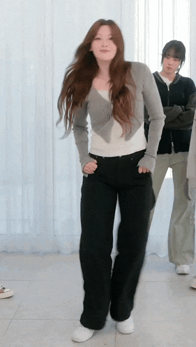 a woman in a gray cardigan and black pants is dancing