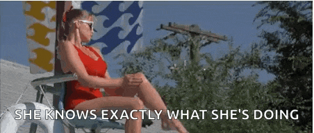 a woman in a red swimsuit is sitting in a chair . she knows exactly what she 's doing .