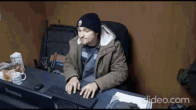 a man is typing on a keyboard in front of an iiyama laptop
