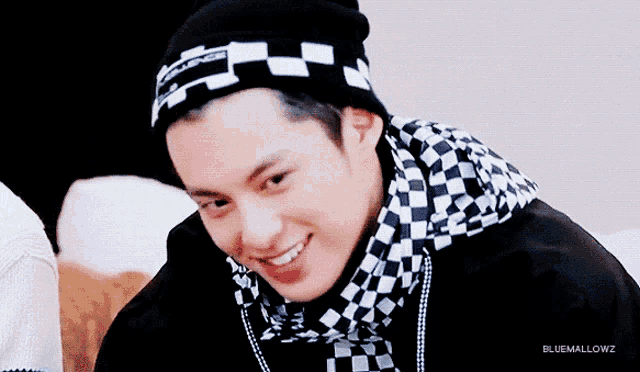a man wearing a black and white checkered jacket and a black beanie