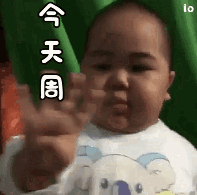 a baby is making a funny face while holding a green object .