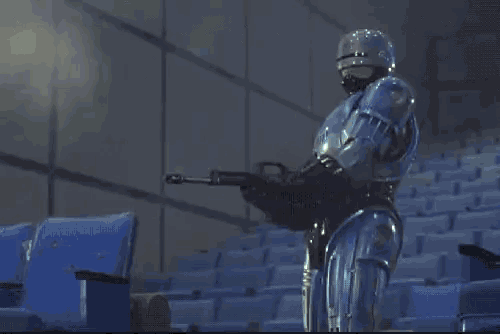 a man in a robot suit is shooting a gun in a dark room