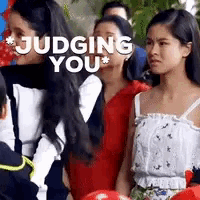 a group of women are standing next to each other with the words judging you behind them .