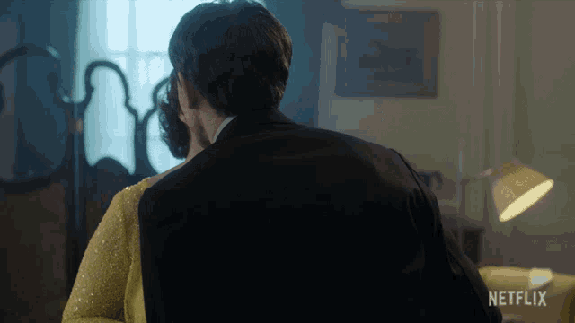 a man in a suit is standing next to a woman in a yellow dress with netflix written on the bottom right