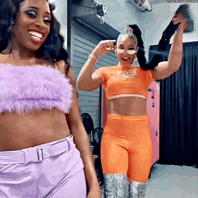 two women are standing next to each other in a locker room and smiling .
