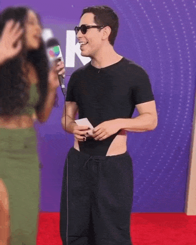 a man is standing on a red carpet with a microphone in his hand