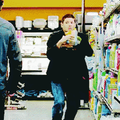 a woman in a black coat is standing in a grocery store