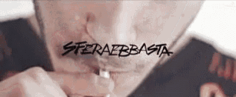 a close up of a man smoking a cigarette with the words sfera basta written on his face .