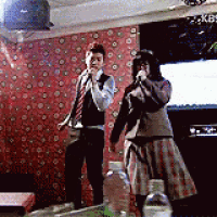 a man and a woman singing into microphones in front of a tv