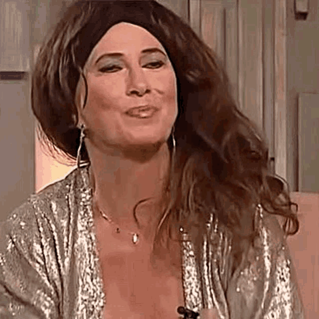 a woman wearing a wig and earrings is smiling while sitting on a chair .