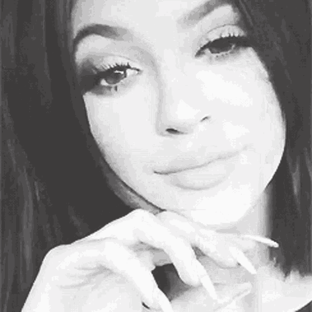 a black and white photo of a woman 's face with long nails .
