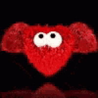 a group of red stuffed hearts with googly eyes are stacked on top of each other on a black background .