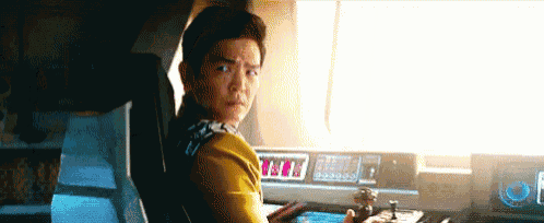 a man in a yellow shirt is sitting at a desk with a clock on it that says 11:11
