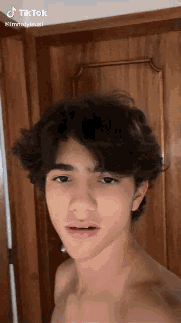 a young man without a shirt is taking a selfie in front of a door .