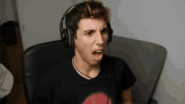 a man wearing headphones and a black shirt with a red moon on it is making a funny face