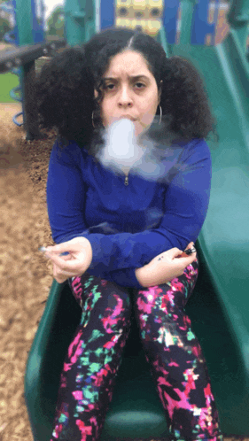 a woman smoking a cigarette while sitting on a slide at a playground