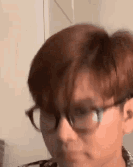 a close up of a person wearing glasses and looking at the camera .