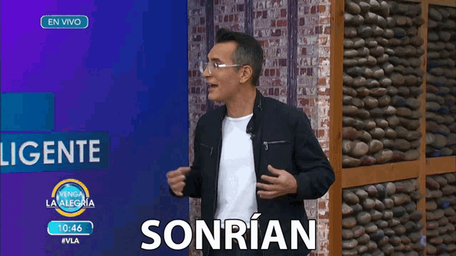 a man stands in front of a stone wall and a sign that says sonrian