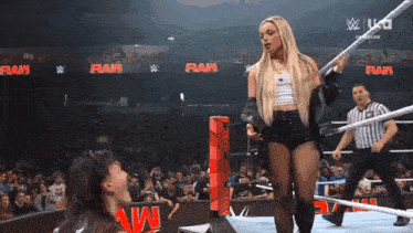 a woman stands in a wrestling ring with the word raw on the wall