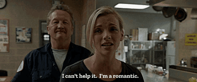 a woman says i can 't help it i 'm a romantic while standing next to a man