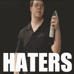 a man holding a spray bottle in front of a sign that says " haters "