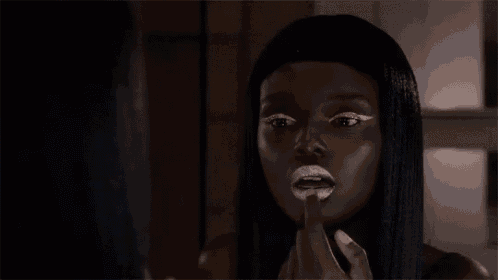 a woman with white lipstick on her lips is looking in the mirror .
