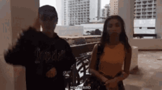 a man and a woman are standing next to each other and the man is wearing a hoodie that says impaler on it
