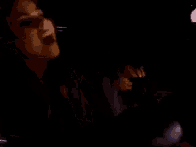 a woman in a suit is sitting in a car with a man in the background .