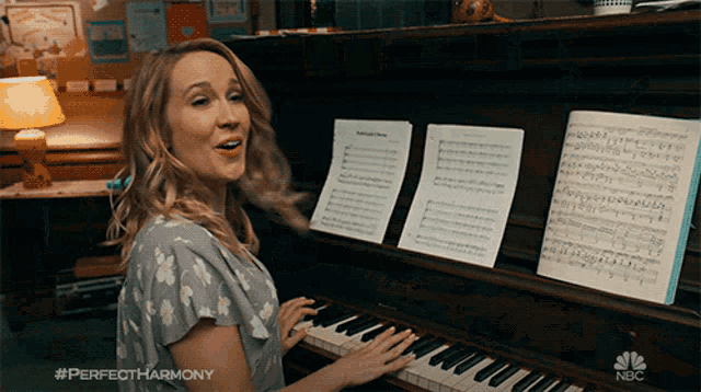 a woman singing while playing a piano with #perfectharmony on the bottom right