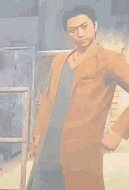 a man in a brown coat and blue shirt is standing with his hands on his hips .