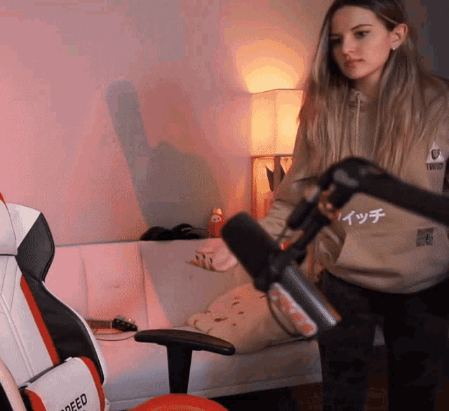 a woman stands in front of a microphone wearing a hoodie that says twitch on it