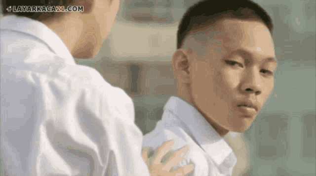 two young men looking at each other with layarnagaxi.com written on the bottom right