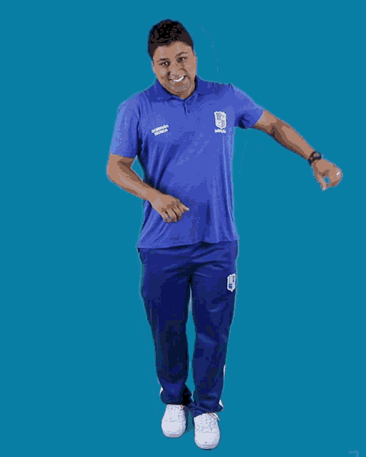 a man wearing a blue shirt that says ' universidad ' on it is jumping in the air