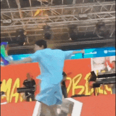 a man in a blue shirt and shorts is dancing on a stage in front of a sign that says ' marlboro '