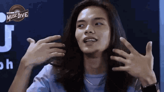 a man with long hair is making a funny face with his hands