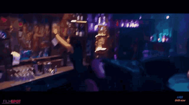 a man is sitting at a bar in a dark room holding a drink .