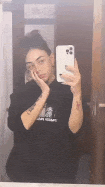 a woman is taking a selfie in a bathroom mirror .