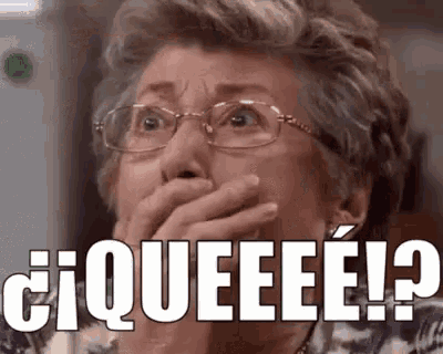 an elderly woman wearing glasses is covering her mouth with her hand and making a surprised face .