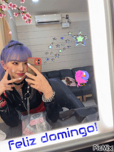 a girl with purple hair takes a selfie in front of a mirror with feliz domingo written on it