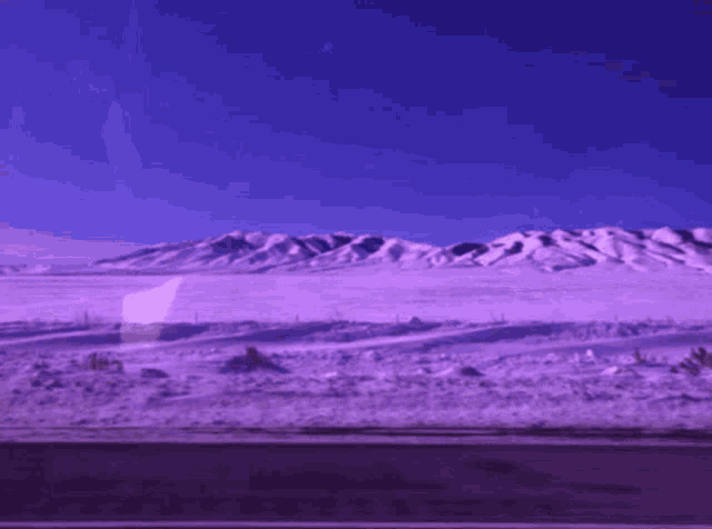 a purple sky with mountains in the background and a road in the foreground