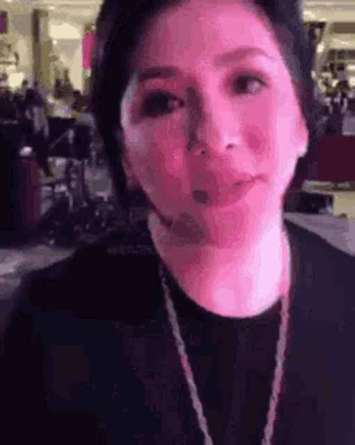 a woman wearing a headset and a necklace is looking at the camera in a blurry photo .