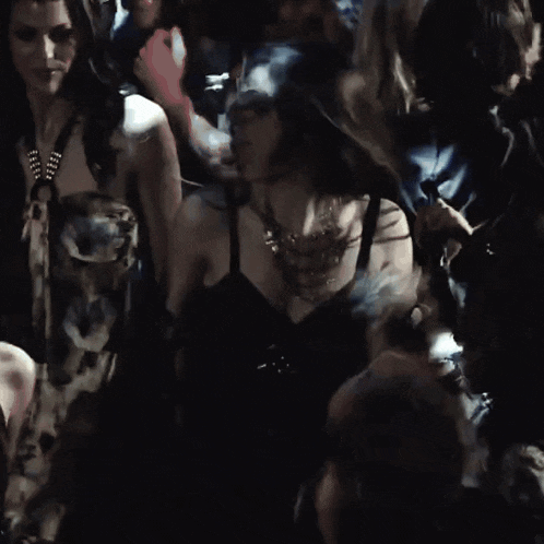 a woman in a black dress is dancing in a dark room