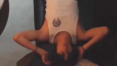 a person is doing a handstand while wearing a white tank top with a horseshoe on it