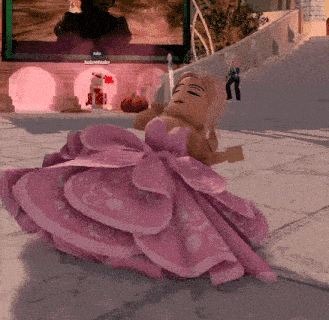 a doll in a pink dress is sitting on the ground in front of a building .