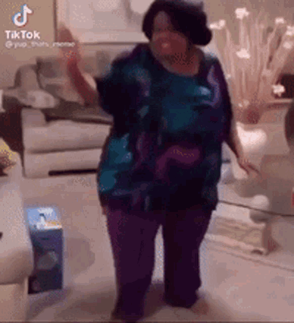 a woman is dancing in a living room in front of a couch and a table .