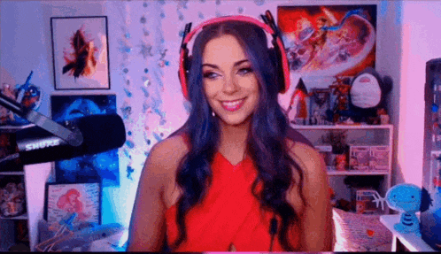 a woman wearing headphones and a red dress is sitting in front of a microphone in a room .