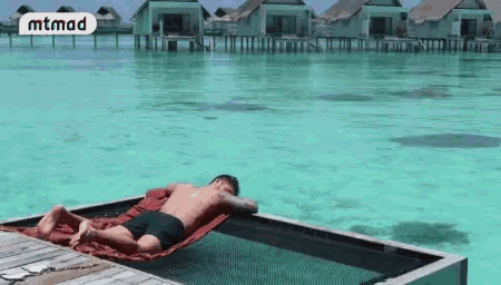 a man is laying in a hammock on a dock in the ocean