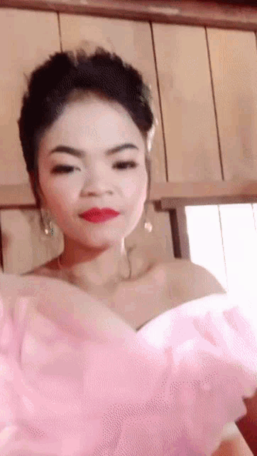 a woman in a pink dress with red lipstick is looking at the camera