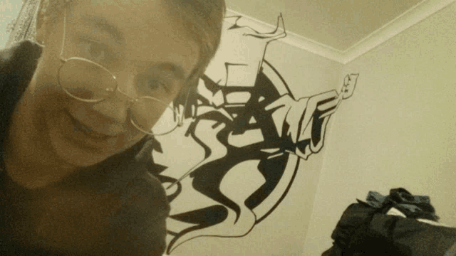 a woman wearing glasses takes a selfie in front of a painting on the wall